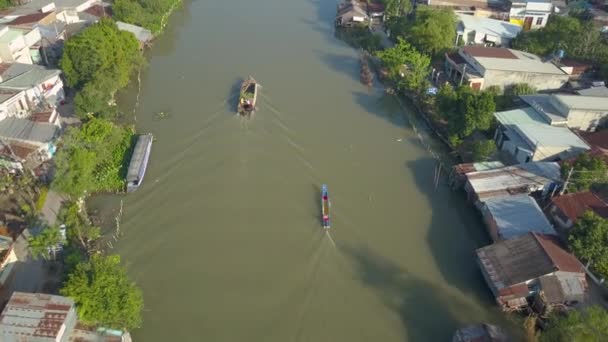 无人机 在田园诗般的亚洲乡村 两艘木船后面巡航而过海滨房屋 流动的市场商人在浑浊的海水边穿过小镇 宁静的当地生活 — 图库视频影像