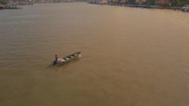 Anten: Nefes kesen bir tropik akşamda sakin nehir boyunca ahşap bir tekne navigasyon yerel kişi boyunca uçan. Altın gün doğumunda Vietnam şehrine gitmek için deltayı geçen kimliği belirsiz kişi.