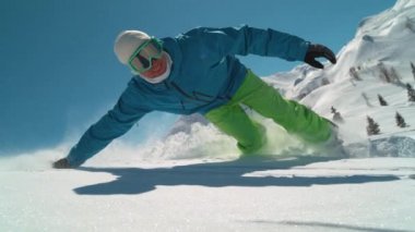 Slow Motion, Close Up: gülümseyen beyaz adam kar taneleri arasında elini sürüklüyor. Kış tatilinde neşeli erkek güneşli bir günde snowboard yaparak ülkeyi boydan boya geçiyor..