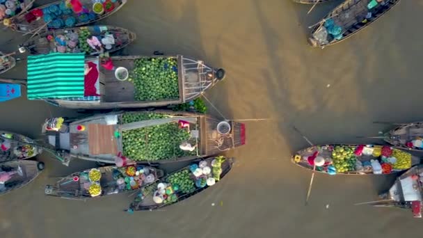 ドローントップダウン ベトナムの田舎の濁ったデルタの周りに浮かぶ木製のボートからカラフルな食材を販売する人々の上を飛ぶ 浮動市場で地元の人々の上からの美しい眺め — ストック動画