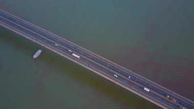 Hava, Yukarıdan Aşağıya: Büyük gemi güneşli Vietnam'da yoğun asma köprü altında yelken. Sayısız araç karanlık nehri geçerken modern otoyol köprüsü yukarı ve aşağı sürüş. Vietnam'da yerel yaşam.