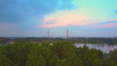 Drone: egzotik orman üzerinde ve ünlü Mekong Nehri ve bu geçiş modern bir asma köprü doğru uçan. Canlı yeşil doğa ve Asya bulanık Nehri geçerken büyük kentsel inşaat.