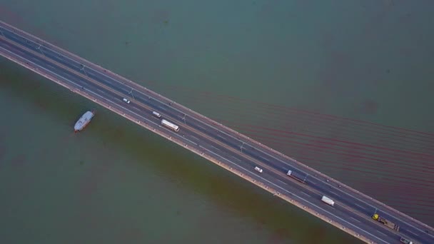自上而下 大型船在阳光明媚的越南繁忙的吊桥下航行 无数的车辆在穿越浑浊的河流的现代公路桥上行驶 越南当地生活 — 图库视频影像