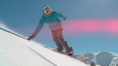 Slow Motion, Close Up, Lens Flare: Genç beyaz kadın güneşli Alplerde kar kayağı yaparken serin bir el sürüme yapıyor. Neşeli bayan turist yeni yağmış toz karı oyuyor..