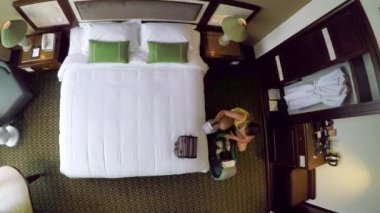 Timelapse, Top Down: Genç kadın gezgin onu seyahat çantası açılır ve kral yatak üzerine elbiselerini açar. Rahat bir tatilde olan Beyaz kadın oteline geldikten sonra bavulunu boşaltıyor.