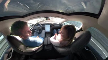 Tesla Autonomous Car, Mart 2018 - Close Up: Yetişkin kadın ve erkek yüksek teknoloji otonom bir araba ile sürüş sırasında birbirleriyle konuşuyor. Bir otoyol boş şeritaşağı bir Tesla tasasız genç çift seyir