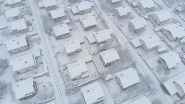 航空写真 雪の街並みや静かな郊外の街の上を飛んでください 新鮮な白い雪で道路吹雪のクールなショット のどかな冬の天候 — ストック動画