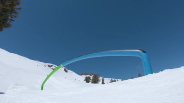 Düşük Açı: Snowboard 'daki atletik adam serin kayak yamaçlarının ortasındaki rayları öğütüyor. Ekstrem snowboardcu, güneşli Squaw Vadisi 'nde kayarken tahtasında kayıyor..