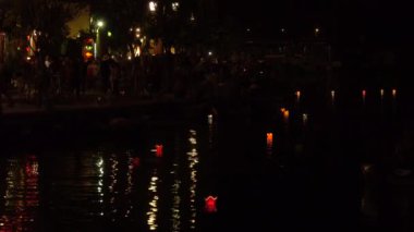 Turistler Vietnam'da sakin bir festival gecesi nde oryantal kağıt lambaları ile dolu nehir boyunca yürümek. Hoi An dolunay festivali sırasında su ve parlayan fenerler tarafından yürüyen insanların Cool shot.