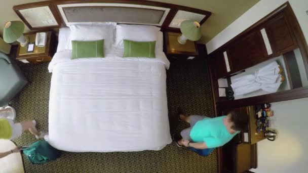 自上而下 在轻松的假期里 漂亮的年轻夫妇倒在他们旅馆舒适的特大号床上 高加索新婚夫妇携带他们的旅行袋进入他们的公寓 跳到床上 — 图库视频影像