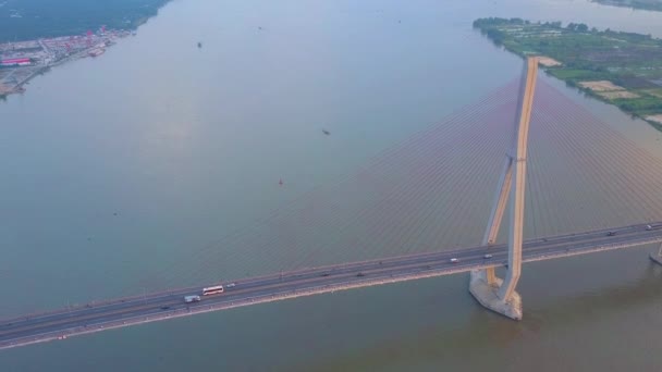 晴れた夜に大きな濁った川を渡る吊り橋の上を高く飛ぶ ベトナムの町と自然を結ぶ高速道路橋を上下する交通の壮大なショット — ストック動画