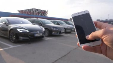 Ljubljana, Slovenya, Mart 2018 - yakın kadar Dof: Tanınmayan kişi yüksek teknoloji Tesla araba ile onların hücre telefon ederek. Araç park yeri dışında direksiyon özerk uzaktan kumandalı.