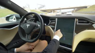 Özerk Tesla arabayı, Mart 2018 - yakın: özerk arabasını dokunmatik ekran konsol üzerinde navigasyon kurma tanınmaz şık kadın. Ekran parmaklarını swiping işkadını.