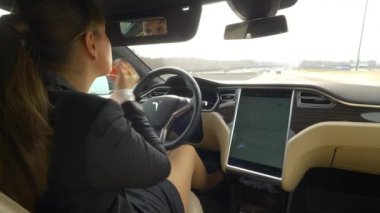 Otonom Tesla Car, Mart 2018 - Close Up: Soğuk otonom bir araçla otobanda giderken kirpiklere maskara uygulayan beyaz kadın. Genç iş kadını işe giderken çoklu görev.