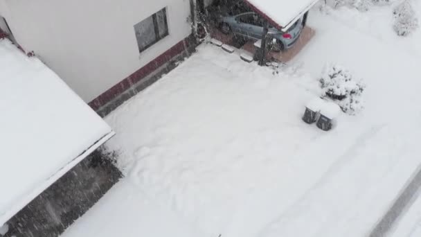 雪の郊外の裏庭を通り過ぎる狭い川の上を飛ぶ 吹雪の間に新鮮な雪に覆われている人々の空の裏庭のクールなショット 冬の初雪 — ストック動画