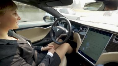 Özerk Tesla araba, Mart 2018 - kadar yakın: Genç şey özerk bir Tesla araç otoyol düşürüyorlardı kadın giyinmiş. Şık beyaz işkadını serin yüksek teknoloji arabasında çalışmaya commuting.
