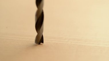 Keskin bir metal matkabın ahşap bir tahtaya delik açarken detaylı görüntüsü..