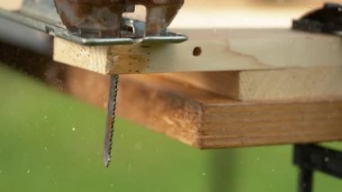 Jigsaw bıçağı marangozun tezgahında otururken kontrplak tahta kesiyor.