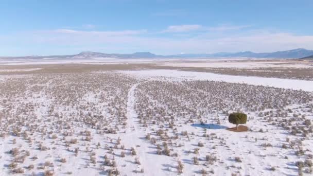AERIAL: Voando sobre as planícies nevadas de Utah e em direção a uma estrada à distância . — Vídeo de Stock