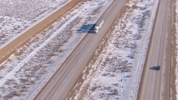 Vit lastbil transporterar last längs den natursköna motorvägen genom snöig öken. — Stockvideo