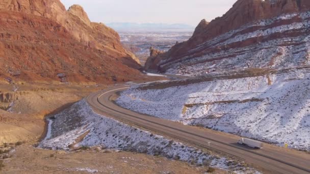 AERIAL: egy teherautó mögött repül, amely rakományt szállít egy téli kanyonon keresztül Utah-ban.. — Stock videók