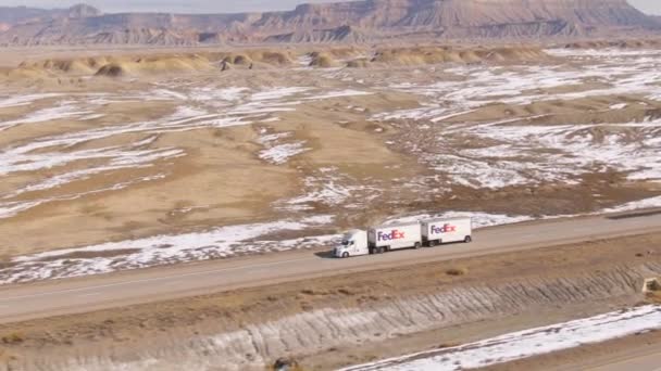 AERIAL: O caminhão FedEx transporta carga pelo deserto nevado de Utah no dia ensolarado de inverno — Vídeo de Stock