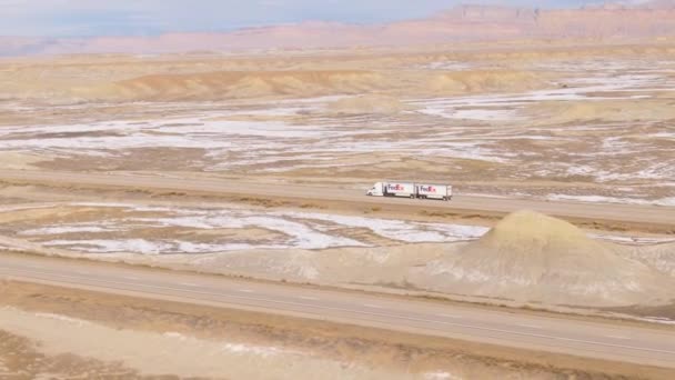 DRONE: Neúrodná zimní krajina obklopuje nákladní automobil FedEx projíždějící Utahem. — Stock video