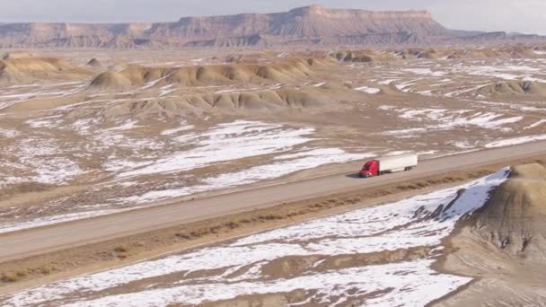 AERIAL: Barren winterse landschap omringt een vrachtwagen rijden over Utah. — Stockvideo