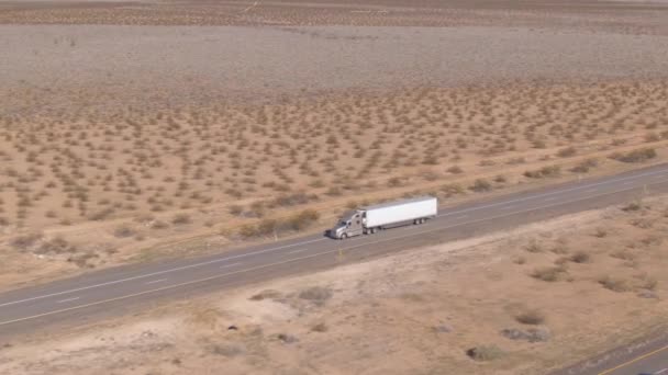 AERIAL: Cinematic skott av en lastbil när den kör ner motorvägen korsar öknen — Stockvideo