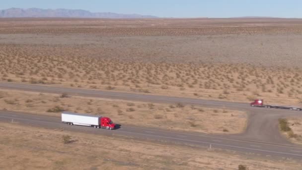 AERIAL: Voando acima de um caminhão de carga vermelho que suporta uma longa viagem através do deserto de Utah . — Vídeo de Stock