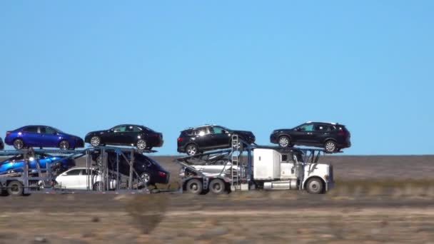 Κοντινό πλάνο: φορτηγό μεταφέρει αυτοκίνητα κάτω από μια εθνική οδό διασχίζοντας την έρημο της Γιούτα. — Αρχείο Βίντεο