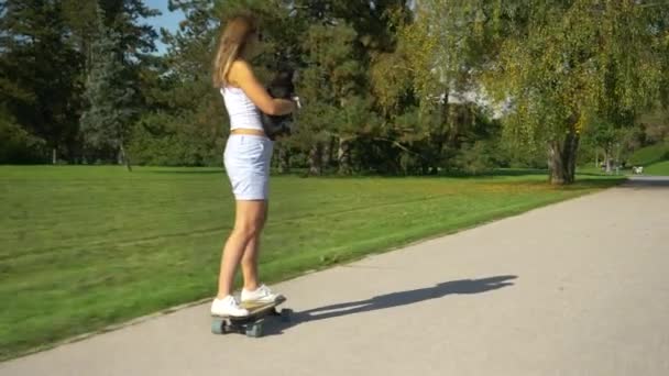 CERRAR: Mujer irreconocible sostiene a su cachorro mientras monta un e-skate — Vídeo de stock