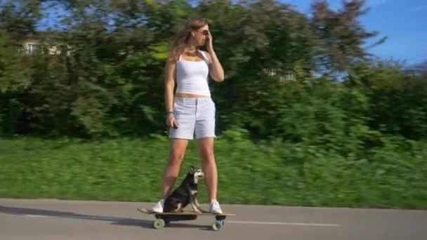 Кавказская женщина наслаждается веселым круизом на электронном скейтборде со своим милым щенком. — стоковое видео
