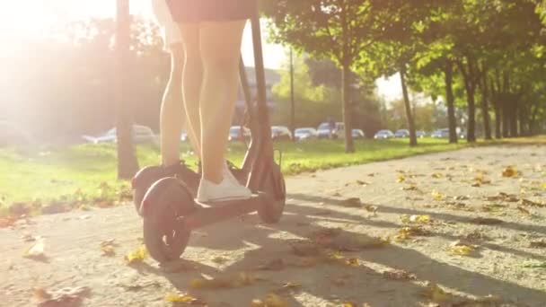 Twee onherkenbare vrouwelijke vrienden rijden op e-scooters langs grindpad.. — Stockvideo