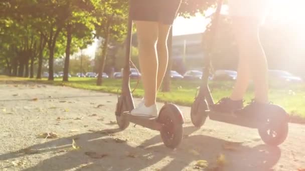 CLOSE UP: Kvinnor rida högteknologiska skotrar runt parken på en solig höstdag — Stockvideo