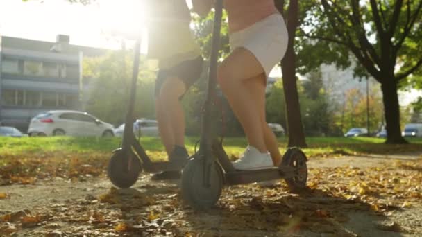 가까이: 알아볼 수없는 두 명의 여성 이 활기찬 거리에서 e-scooters 를 타기 시작 한다. — 비디오