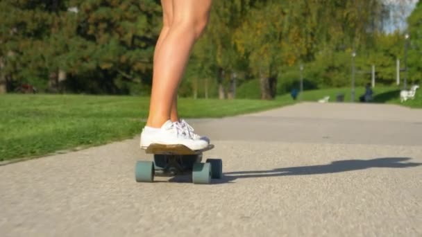 低角度：无法辨认的女人骑着电动长板绕着阳光充足的公园转. — 图库视频影像