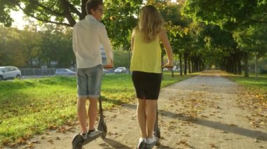 Kaygısız çift güneşli bir sonbahar gününde elektrikli scooter kullanıyor..