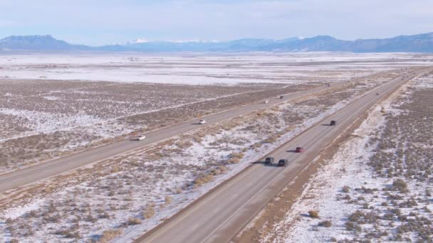 空気:雪の砂漠を横断するアスファルト高速道路の先頭車両の上を飛ぶ — ストック動画