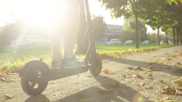 STÄNGA UPP: Oigenkännlig man rider en elektrisk skoter ner en naturskön grusväg — Stockvideo