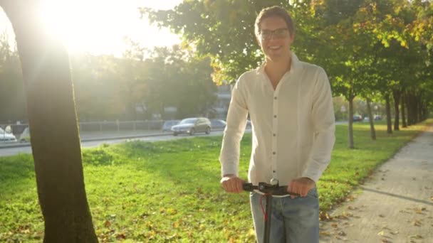LENS FLARE: Scatto cinematografico di un uomo che guida uno scooter elettrico in una giornata di sole . — Video Stock