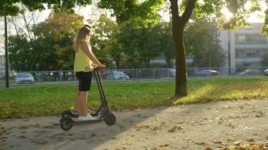 Güneş ışığı E- scooter kullanan çiftlerin üzerinde parıldıyor. Manzaralı yürüyüş yolunda.