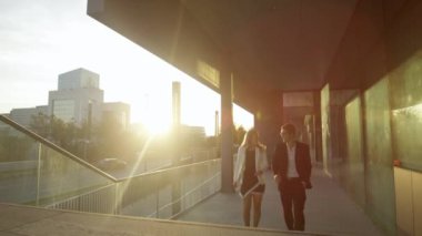 İş ortakları güneşli finans bölgesinde yürürken sohbet ediyorlar.