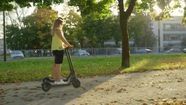 太陽のフレアゴールデンサンビームは、風光明媚な歩道に沿って2人乗りのe-scootersに輝きます — ストック動画
