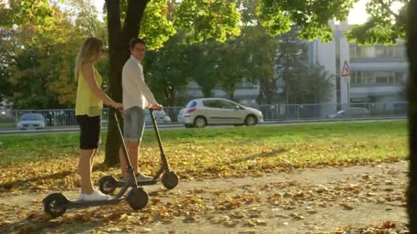 Lente FLARE Hombre y mujer hablan mientras disfruta de un paseo en scooter por la colorida avenida — Vídeos de Stock