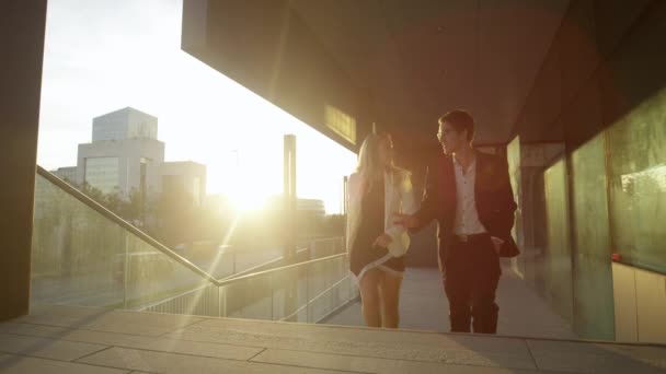 CLOE UP: Бізнес-леді і колега говорять під час прогулянки додому з роботи на заході сонця — стокове відео