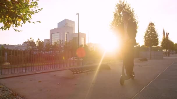 COPY SPACE: Un hombre de negocios sonriente monta un e-scooter para trabajar en una mañana soleada. — Vídeo de stock