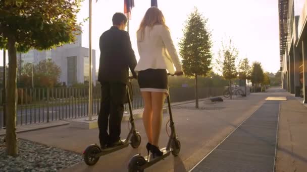 SLOW MOTION: Young business partners chat while riding their e-scooters to work. — Stock Video