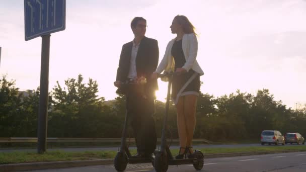 Dua manajer berbicara dan naik skuter listrik mereka untuk bekerja saat matahari terbit — Stok Video