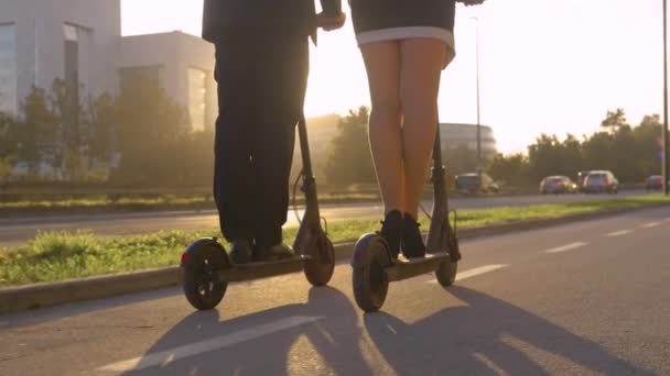 低角度:若い企業の専門家は、日の出に動作するようにe-scootersに乗る. — ストック動画